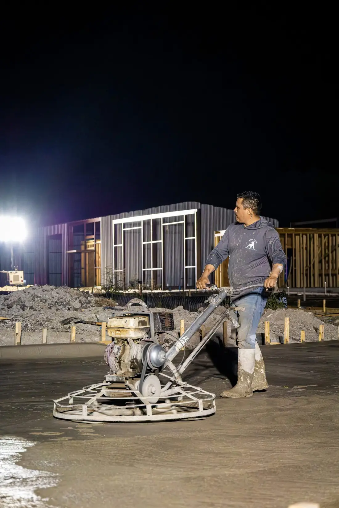 Western Star Concrete crew member using a power trowel to finish a commercial concrete slab at night